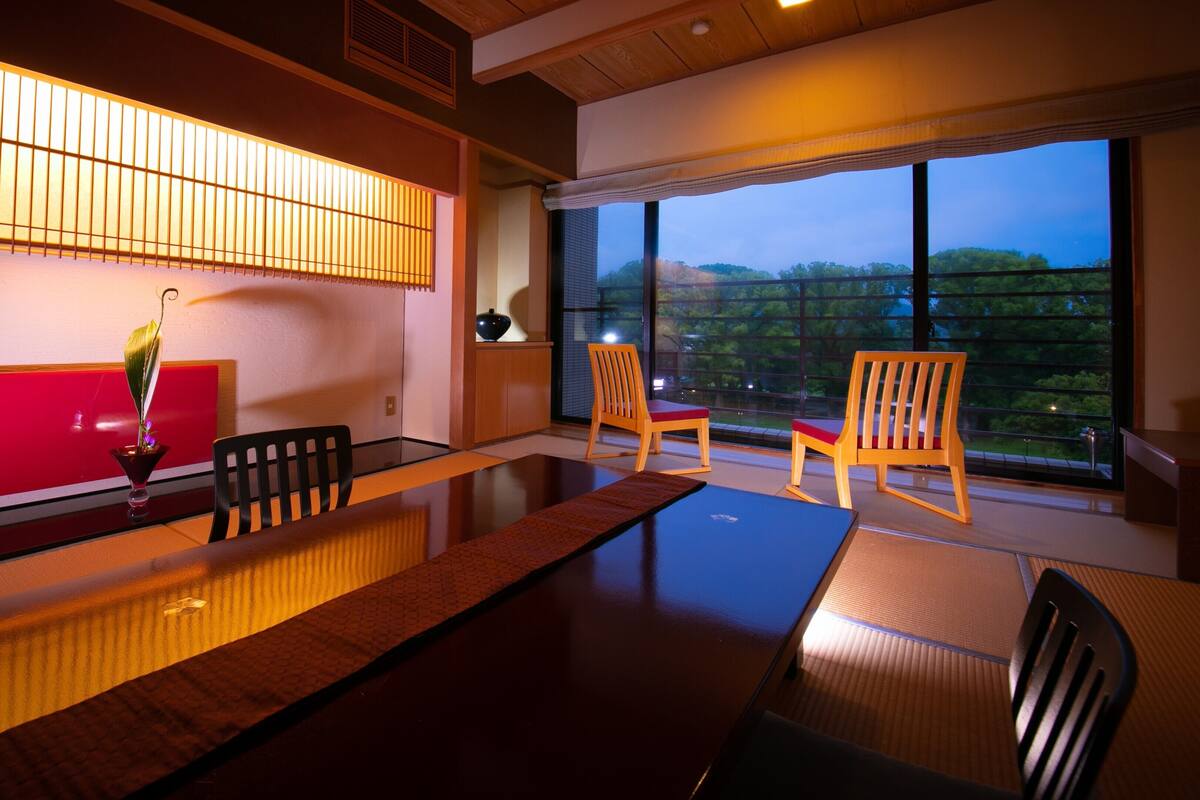 A traditional Japanese-style room with tatami flooring, a low table, and wooden chairs.