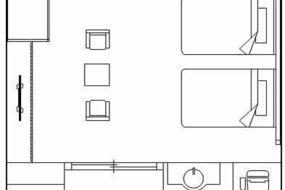 A hotel room layout with a bed, a desk, a chair, a small table, and a bathroom area.