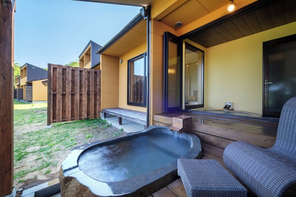 Un espacio de spa con jacuzzi, terraza de madera y asientos.