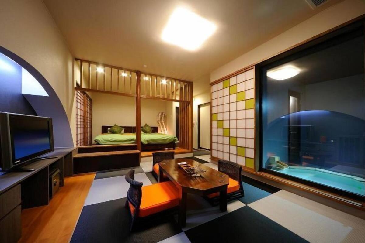 Una habitación de hotel pequeña con cama, televisor, mesa de comedor y puerta corrediza.