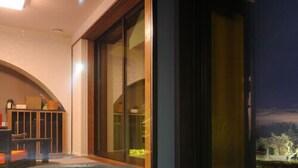 A modern indoor swimming pool with a view of a night landscape through large sliding doors. - Ryusen Bettei Kanzanchogetsu (Kawasaki)