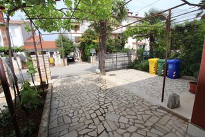 A paved courtyard with stone tiles, a metal fence, and potted plants. - Apartments Villa Buric (Rovinj)