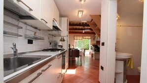 Una cocina moderna con armarios blancos, electrodomésticos de acero inoxidable y un comedor con mesa y sillas.