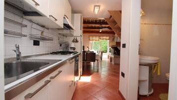 Una cocina moderna con armarios blancos, electrodomésticos de acero inoxidable y un comedor con mesa y sillas.