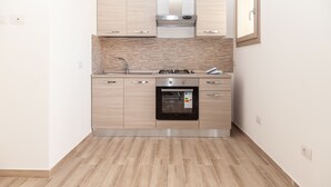 A modern kitchen with light wood cabinets, a stainless steel range hood, a built-in oven, and a tiled backsplash. - Aria di Vacanza - S'Abba Lughente Trilo (Olbia)