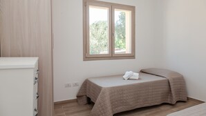 A bedroom with a single bed, a window, and a wooden wardrobe. - Aria di Vacanza - S'Abba Lughente Trilo (Olbia)