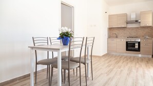 A modern kitchen with a dining table and chairs, a built-in oven, and a backsplash. - Aria di Vacanza - S'Abba Lughente Trilo (Olbia)