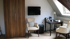 Een kamer met een houten garderobe, een aan de muur bevestigde televisie, een bureau met een computer en twee stoelen.