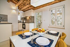 Una cocina moderna con armarios blancos, techo de madera y un comedor con mesa para dos.