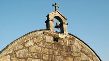 A stone dome with a bell tower and cross.