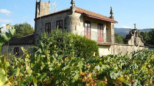 Un bâtiment en pierre avec un toit recouvert de tuiles rouges, un clocher et une petite cloche.