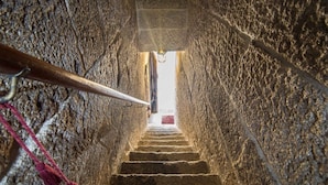 Un escalier en pierre menant vers le haut, bordé de murs en pierre brute.