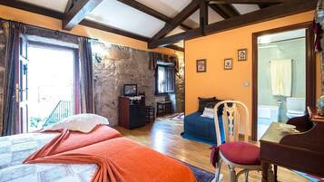 Une chambre avec un lit, un bureau, une chaise, une petite table et un mur en pierre.