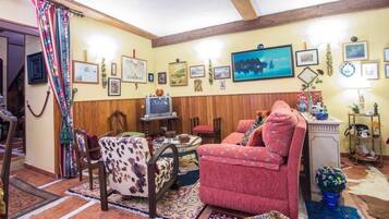Una sala de estar acogedora con televisor, sofá y comedor con mesa y sillas.