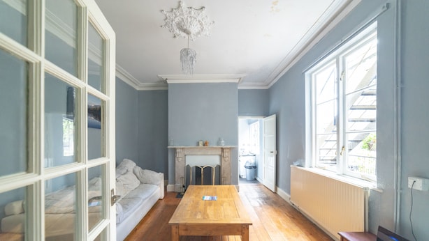 A room with a wooden table, a sofa, and a fireplace. - Stag and Hen Friendly House (Bath)