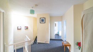 A hallway with carpeted floors, a staircase, and a door leading to another room. - Stag and Hen Friendly House (Bath)