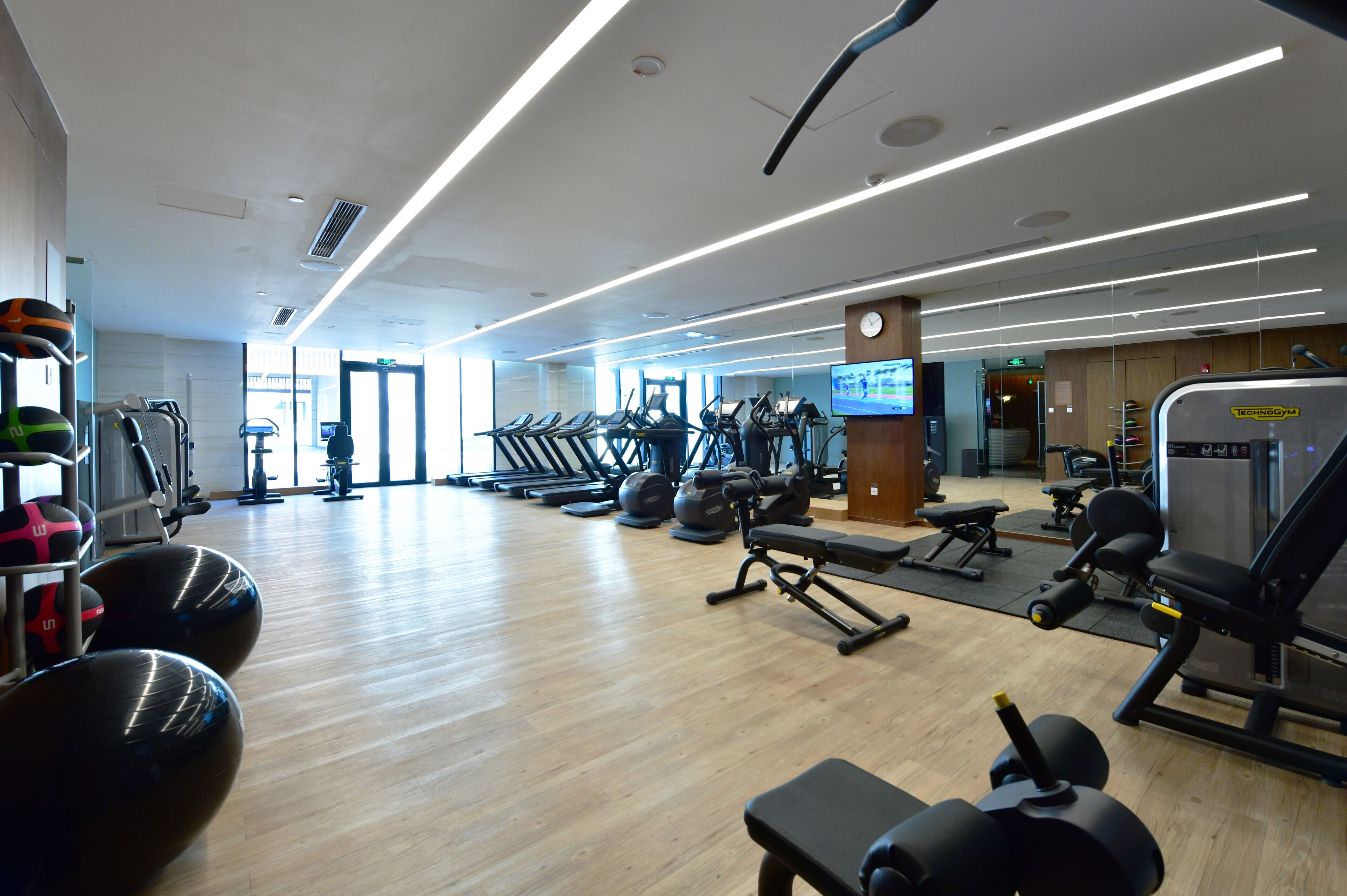 Un gimnasio con cintas de correr, máquinas de pesas y pelotas de ejercicio.