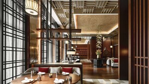 Een modern restaurantinterieur met houten vloeren, een centraal eetgedeelte met ronde tafels, en een bar met een hoge toonbank.