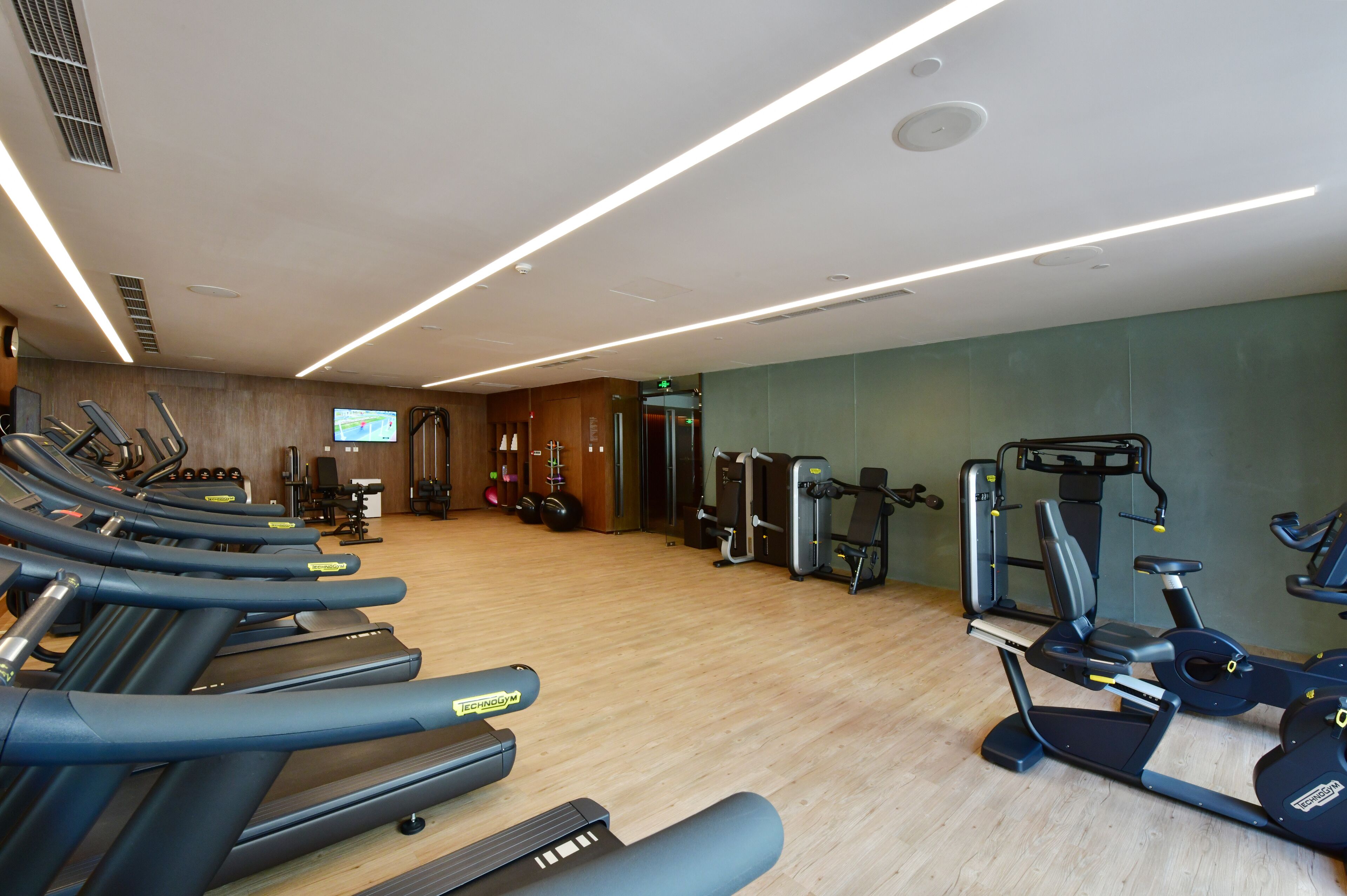 Een fitnessruimte met loopbanden, elliptische trainers en gewichten.