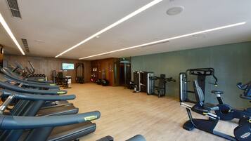 Een fitnessruimte met loopbanden, elliptische trainers en gewichten.