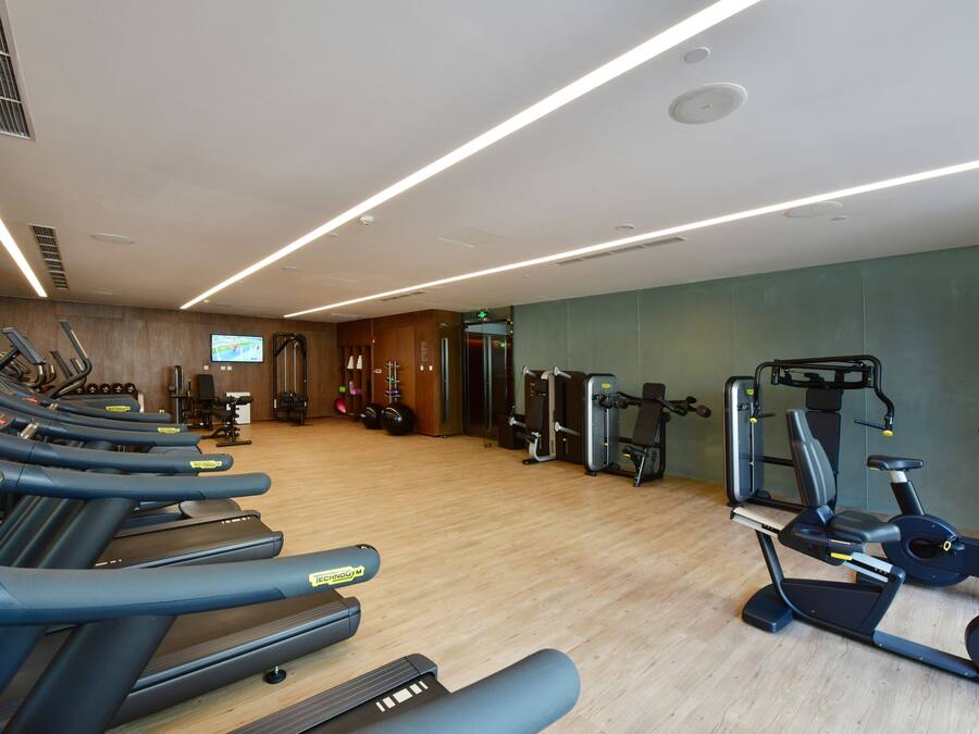Een fitnessruimte met loopbanden, elliptische trainers en gewichten.
