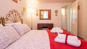 Une chambre d’hôtel avec un lit, une commode, un miroir et une moquette rouge.