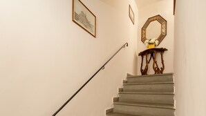 Un escalier avec une rampe, un miroir fixé au mur et des œuvres d’art encadrées.