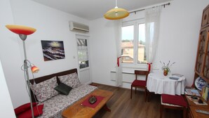 Una sala de estar acogedora con un sofá, una mesa de madera, una lámpara de pie y una ventana con cortinas.