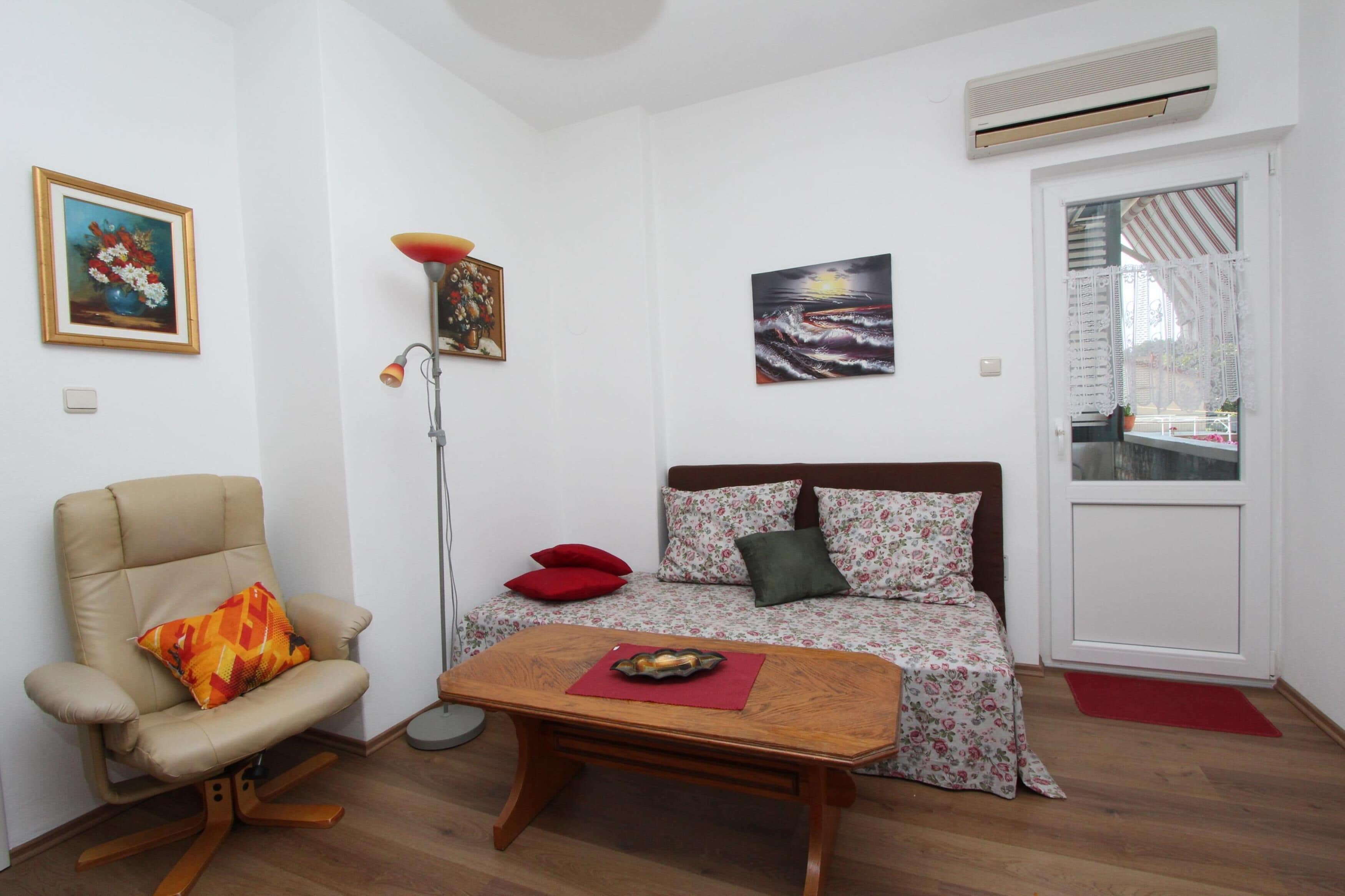 A small, well-lit room with a sofa, a chair, a table, and a painting on the wall.