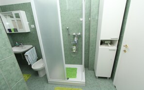 A bathroom with a shower, toilet, sink, and a cabinet. - Apartment Dina (Rovinj)