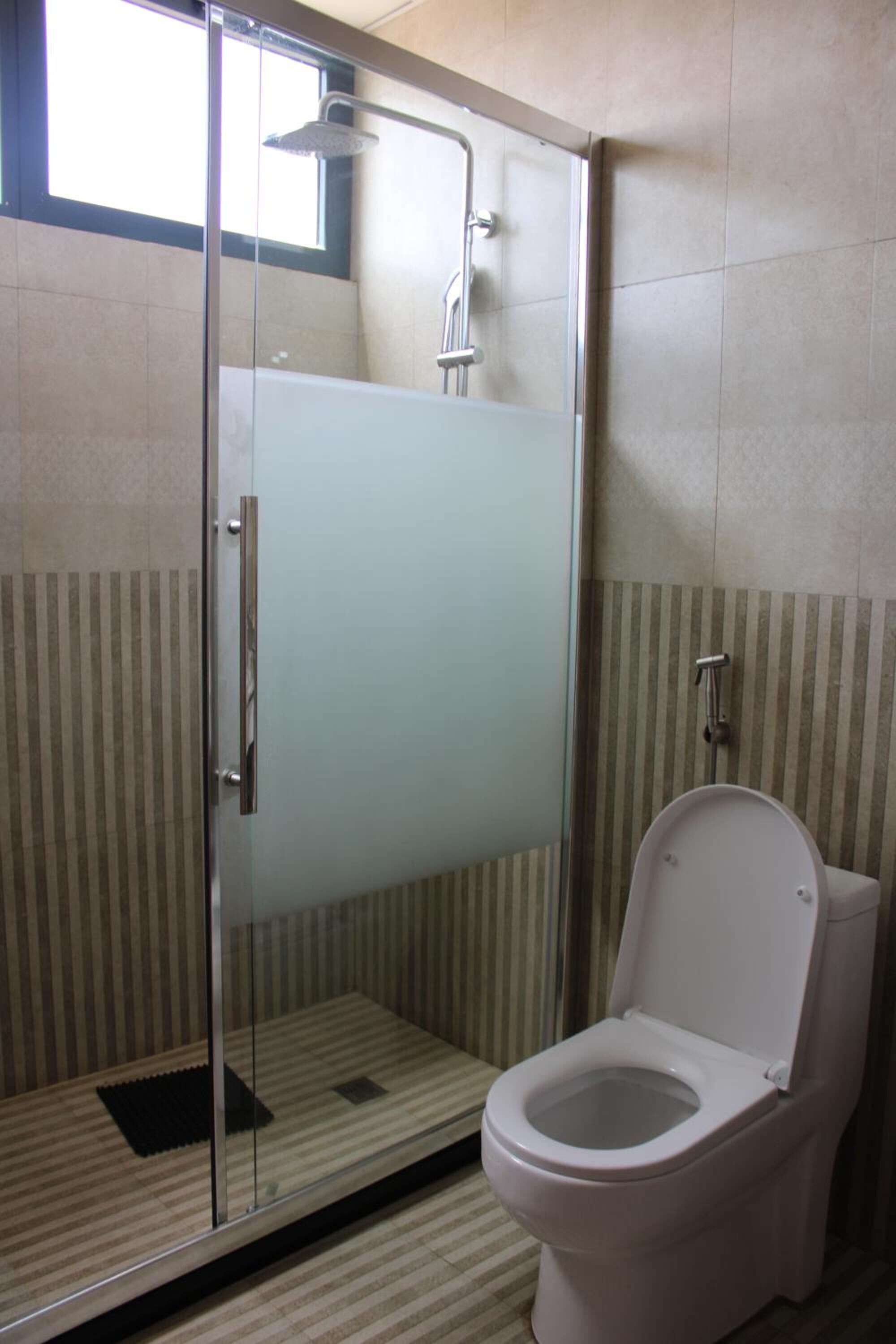 Een badkamer met een glazen douchecabine, toilet en gestreepte wanden.
