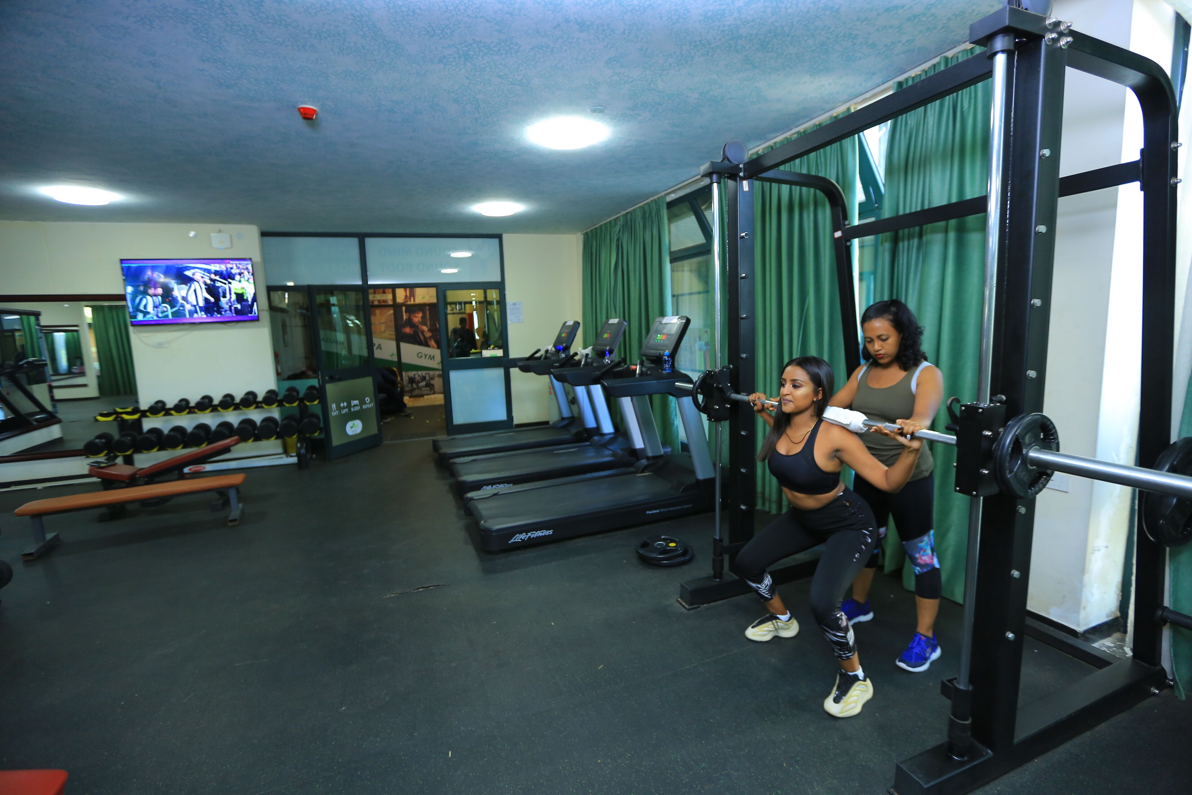 Un gimnasio con cintas de correr, máquinas de pesas y mancuernas.