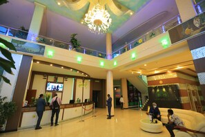 A hotel lobby with a reception desk, a chandelier, multiple floors, and a seating area. - Unison Hotel and Spa (Bahir Dar)
