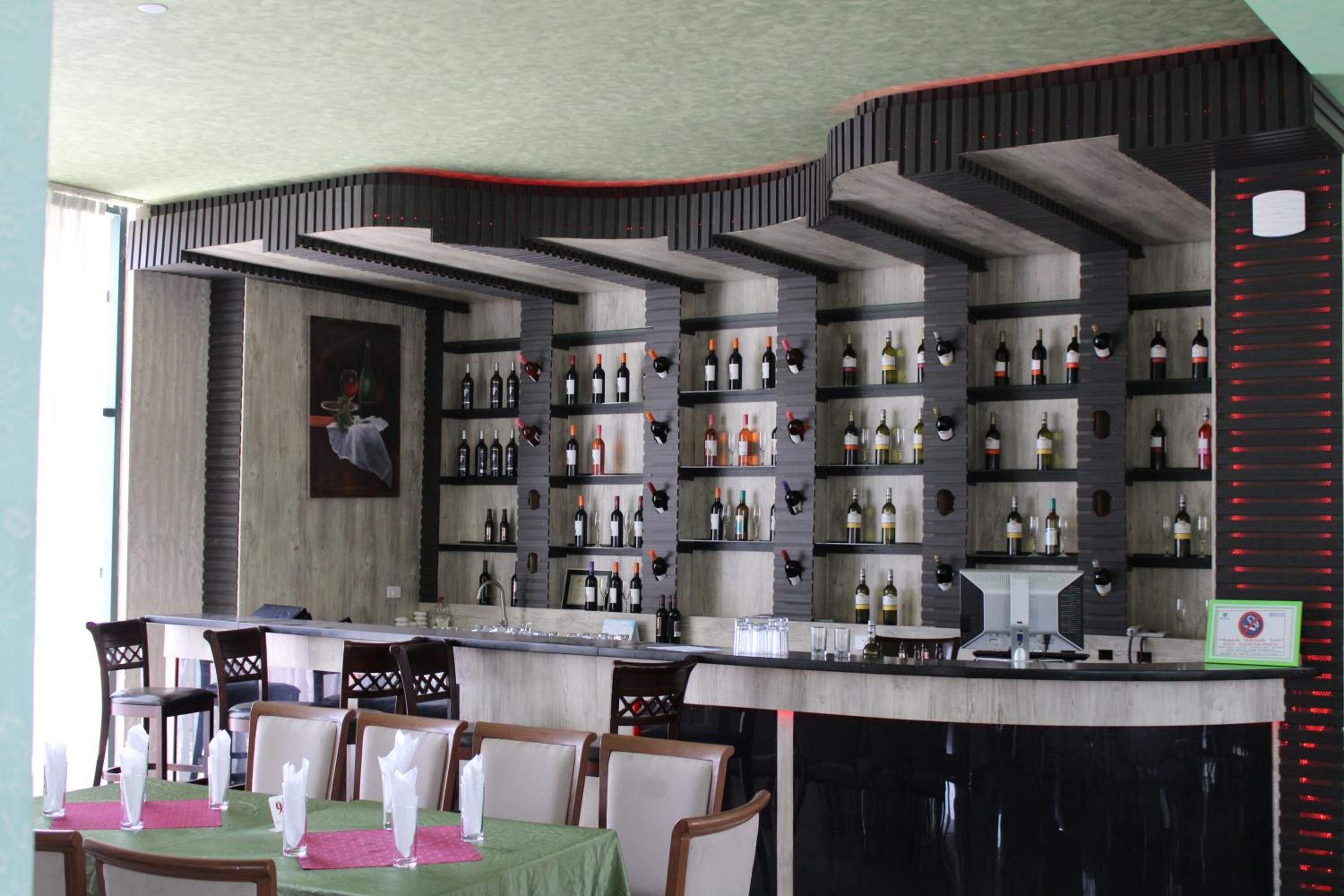 A restaurant with a bar area, multiple seating arrangements, and a variety of wine bottles displayed on shelves.