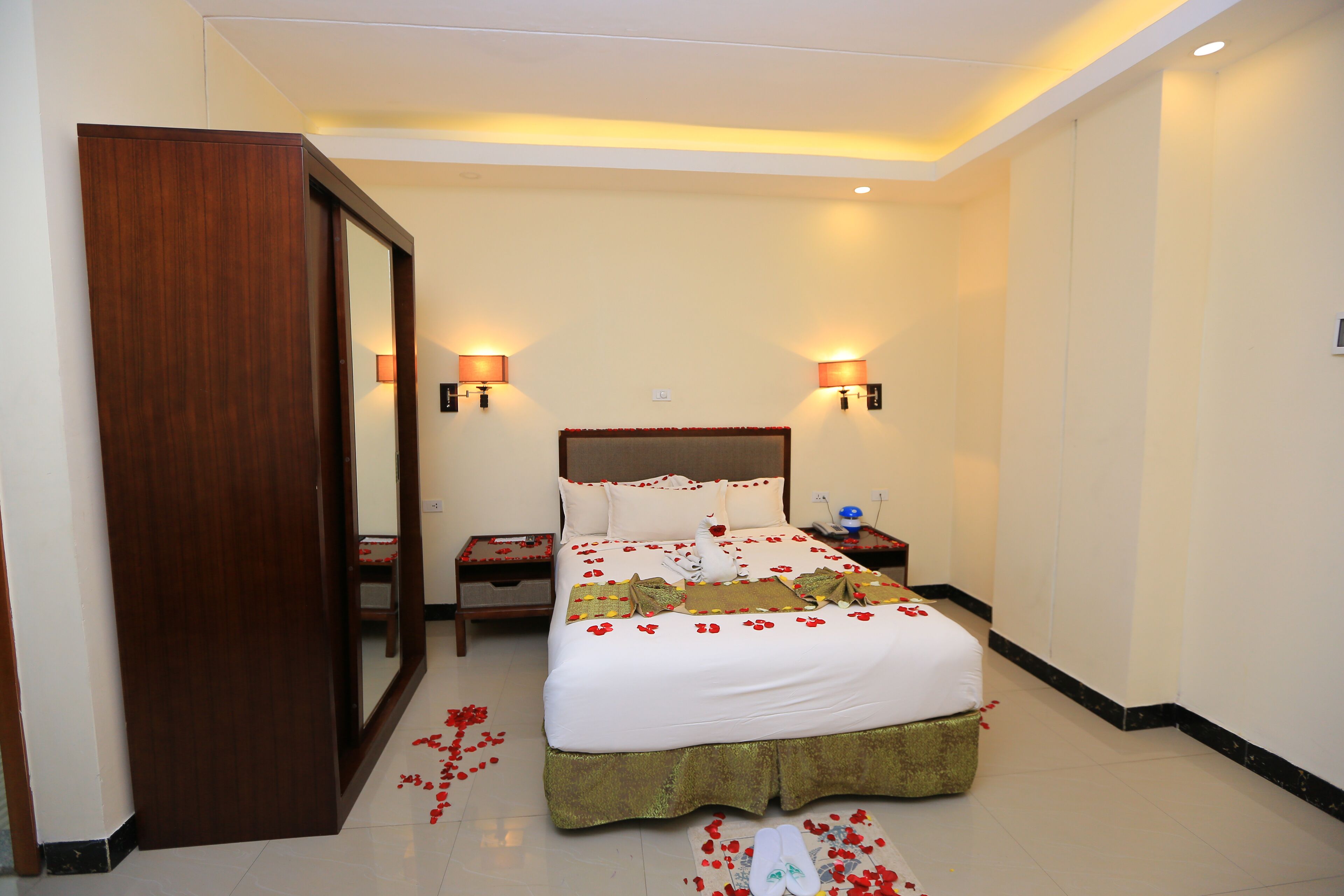 Habitación de hotel con una cama grande, dos lámparas de noche, una mesita de noche y un espejo.