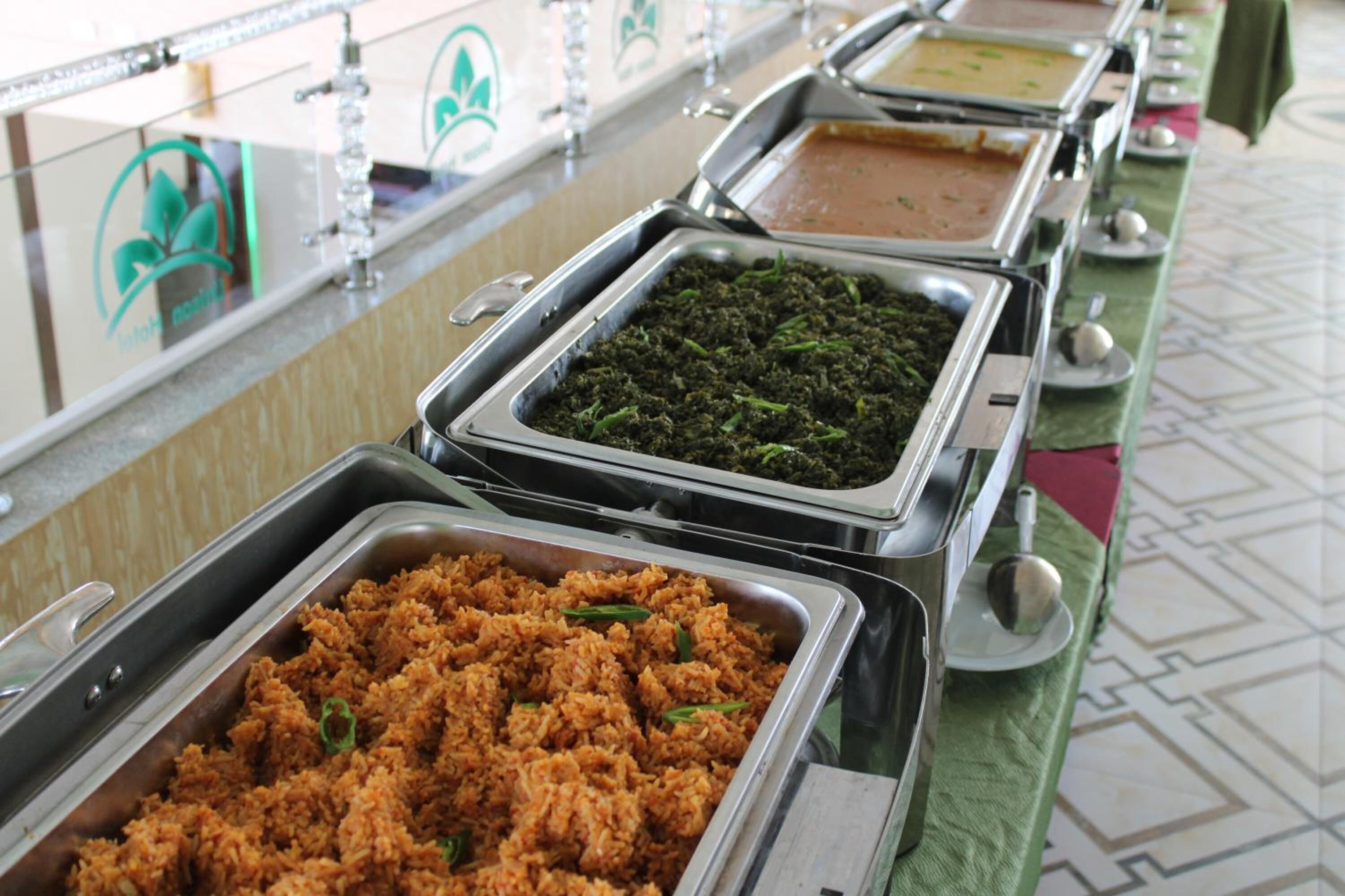 Een buffet met diverse gerechten, zoals rijst, groenten en bruine saus.