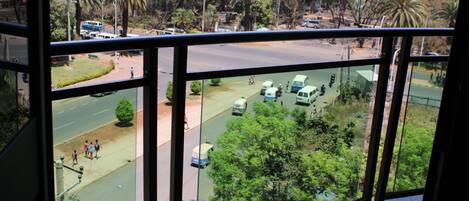Vista desde una ventana que da a una calle con palmeras y un paisaje montañoso.