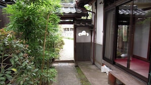 A traditional Japanese building with a wooden walkway, a stone path, and a bench.