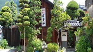 A traditional wooden building with a sign, surrounded by well-maintained greenery and a gravel path.