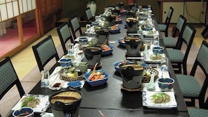 A long dining table with multiple bowls and plates of food, arranged for a meal.