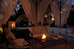 An outdoor seating area with a sofa, chairs, and a table with candles and books. - Hotel La Corte (Bedizzole)
