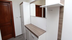 A compact room with a wooden door, a white cabinet, and a small countertop. - Apartment Ilinovic (Rovinj)