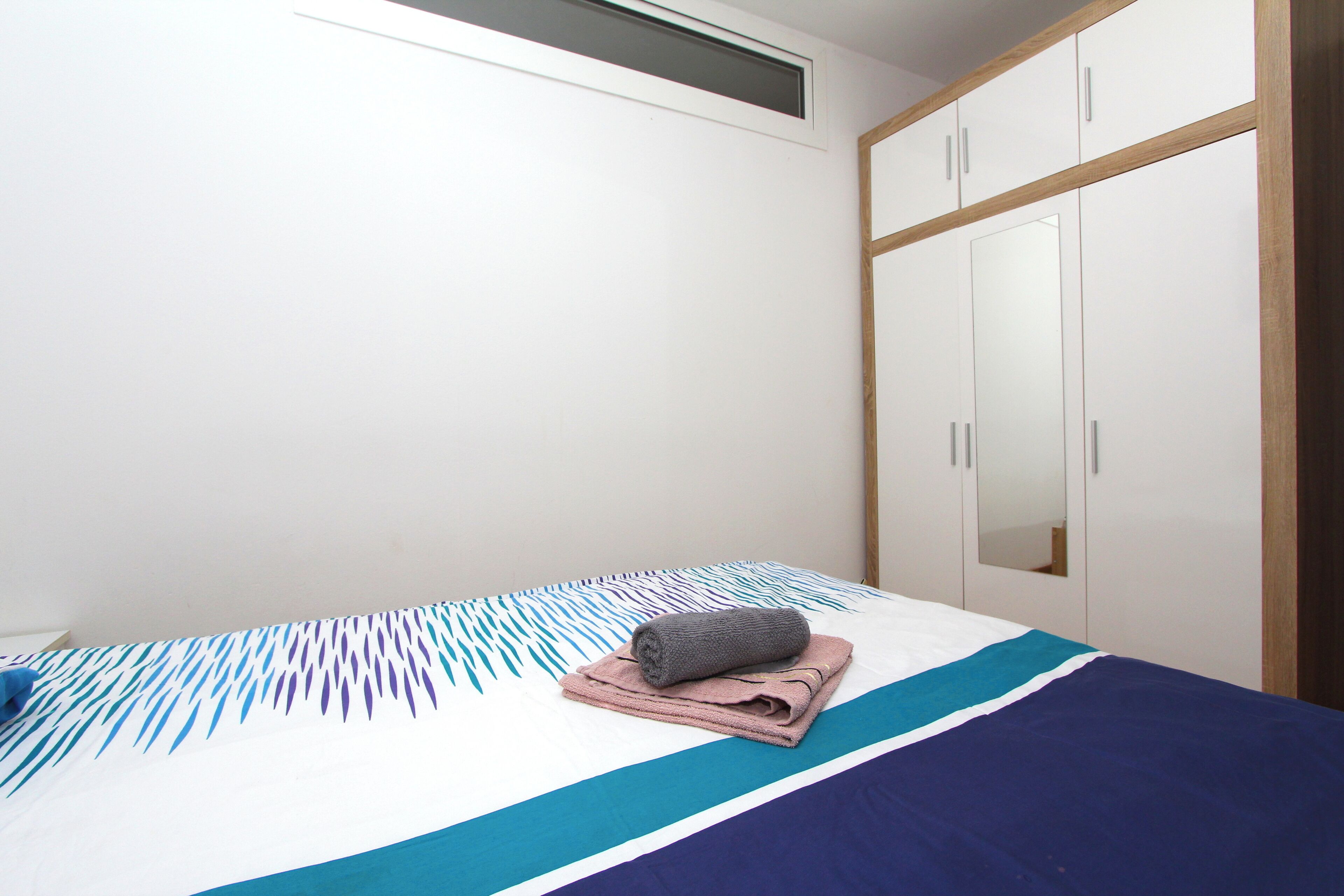 A bedroom with a bed, a wardrobe, and a mirror.