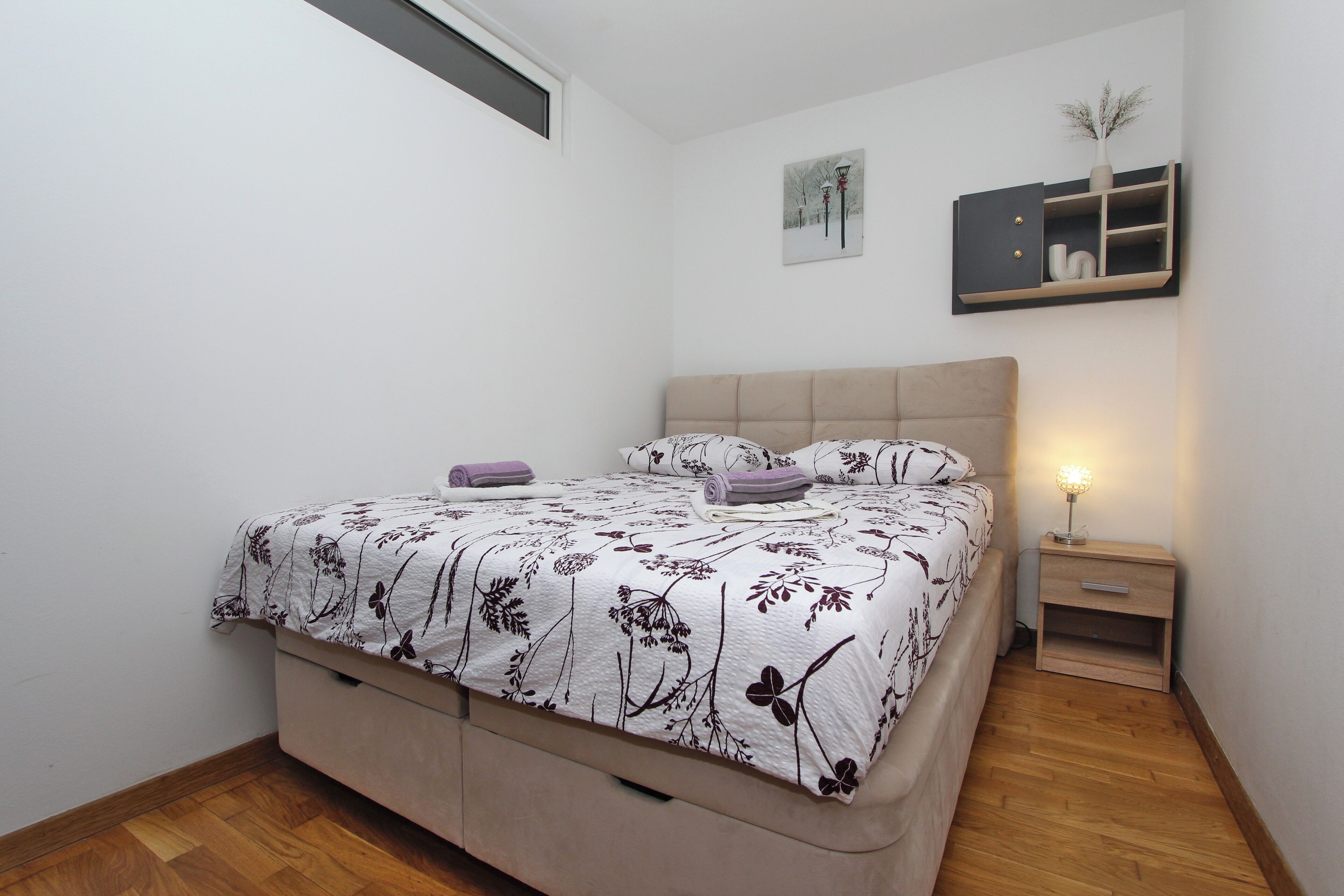 Una camera da letto con un letto, comodini, un piccolo tavolo e una mensola a parete.