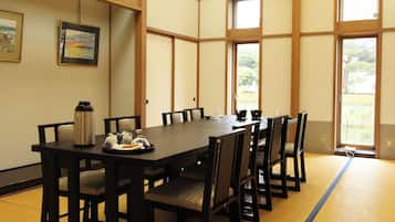 A traditional Japanese-style room with tatami flooring, a low table, and black chairs.