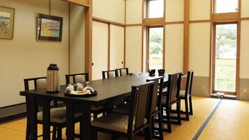Una habitación al estilo japonés tradicional con suelo de tatami, una mesa baja y sillas negras.