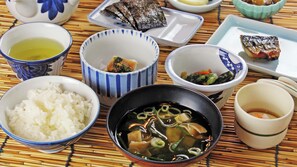 Variedad de platos japoneses, como arroz, sopa y pescado, servidos sobre una estera de bambú.