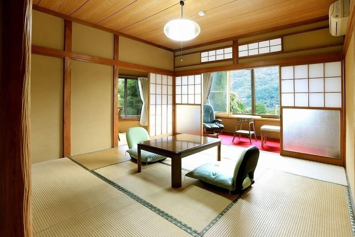 A traditional Japanese room with tatami flooring, a low table, and sliding doors.