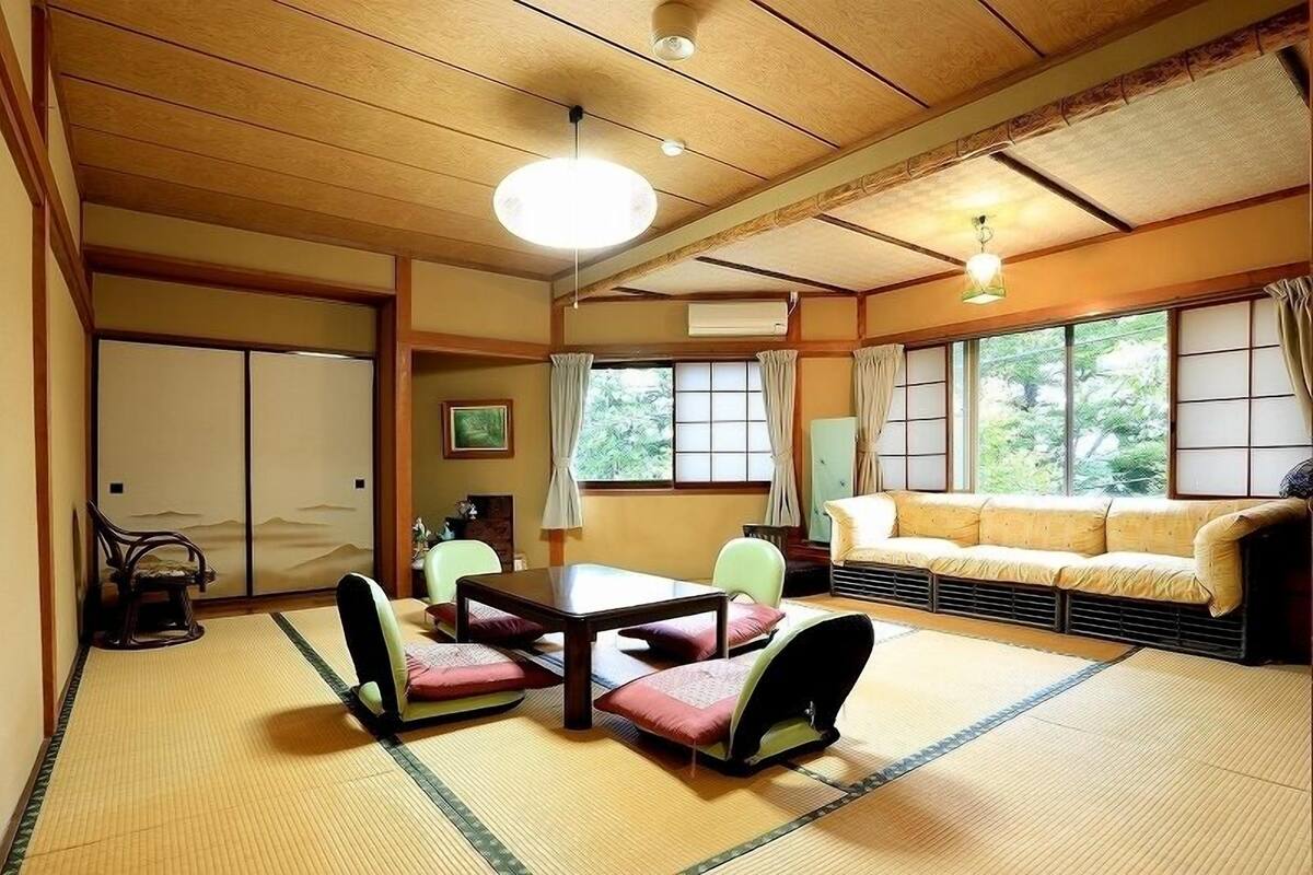 A traditional Japanese room with tatami flooring, a low table with cushions, a sofa, and sliding doors.