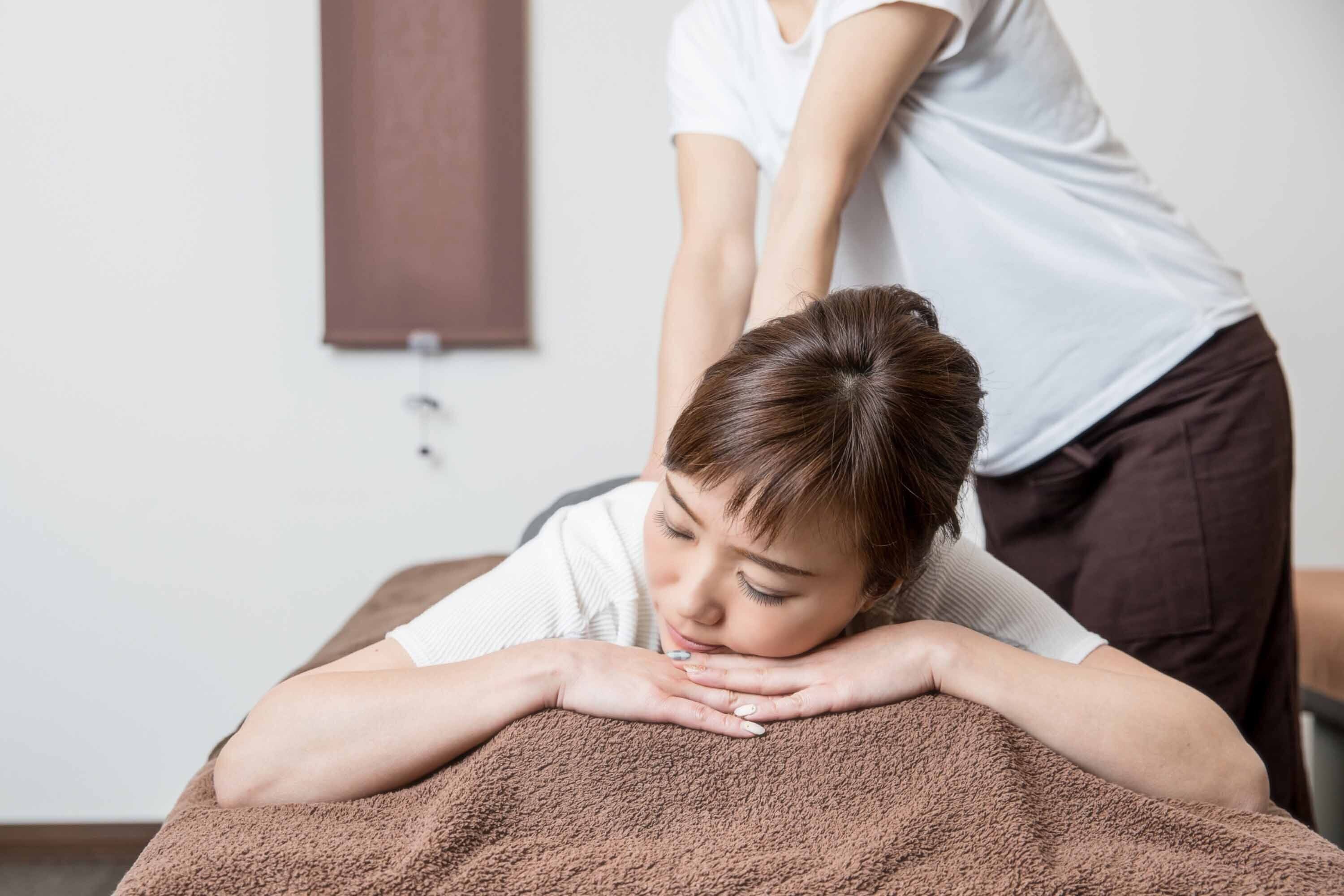 A massage therapy session in a room with a brown blanket on the massage table.